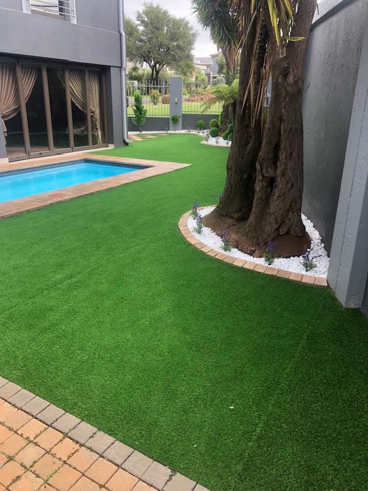 Backyard with swimming pool, artificial lawn and landscaped tree bed