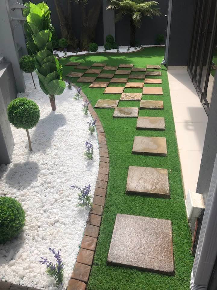 Side yard with stepping stone path, white pebbles and topiary trees