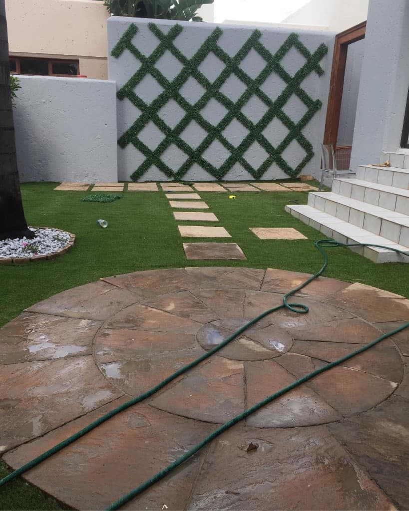 Circular stone patio with grid stepping stones and green trellis wall