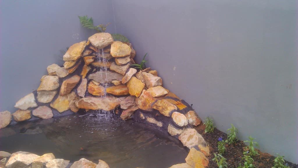 Curved garden bed with brick edging, lavender and black metal fence
