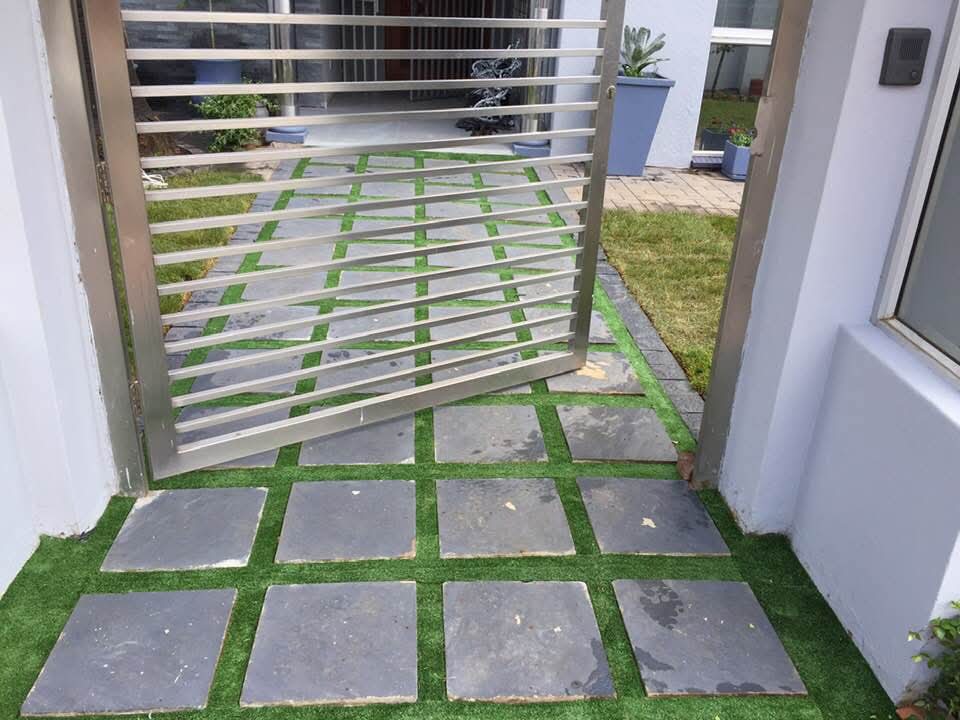 Modern metal gate with slate and turf grid entrance walkway