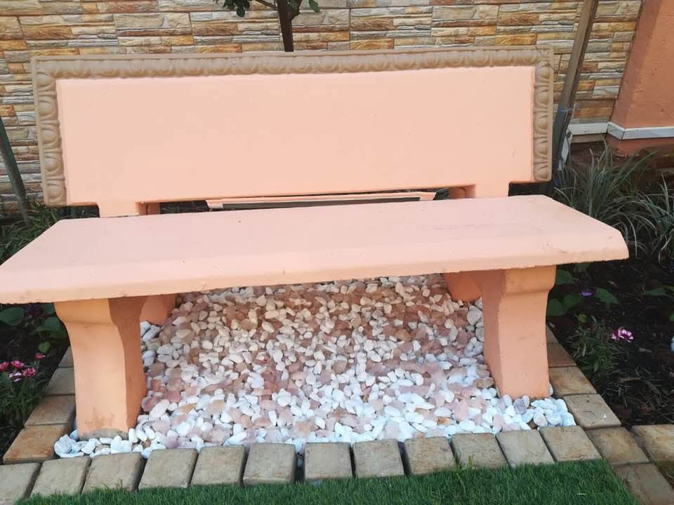 Decorative garden bench set in white pebbles against stone wall