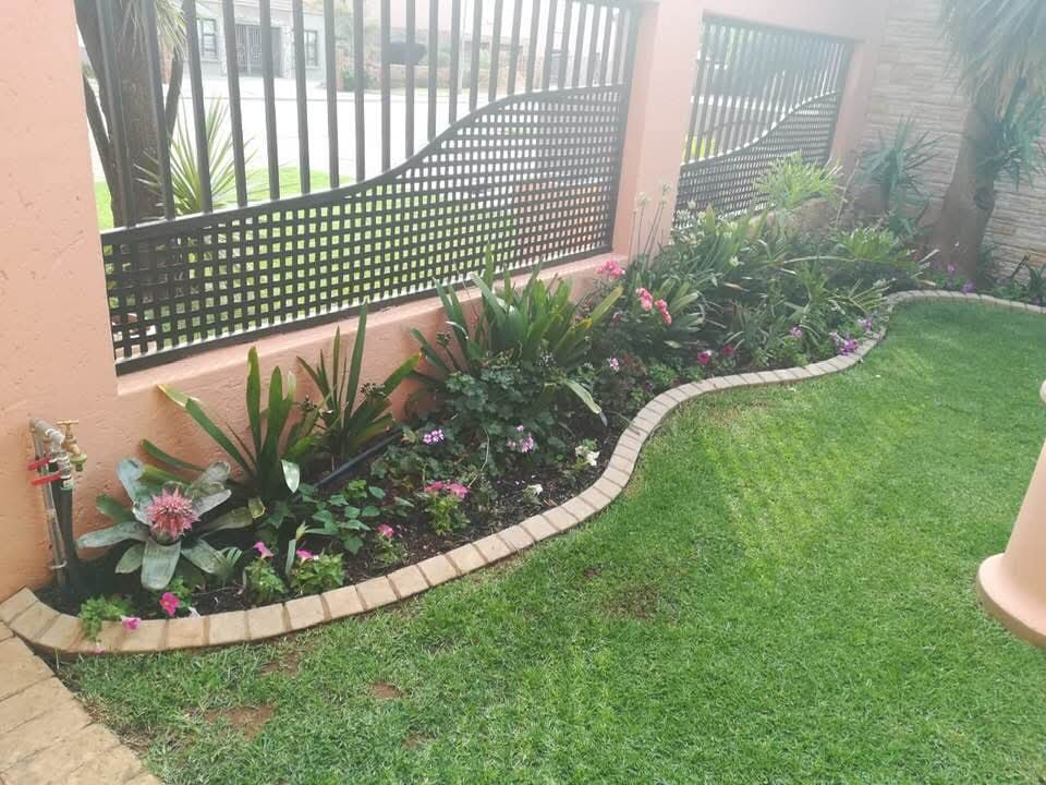 Curved flower bed with decorative wall fence and brick edging